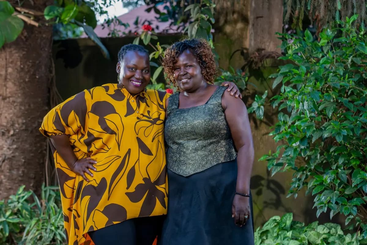 Deux femmes souriantes et complices, en tenues colorées, dans un jardin