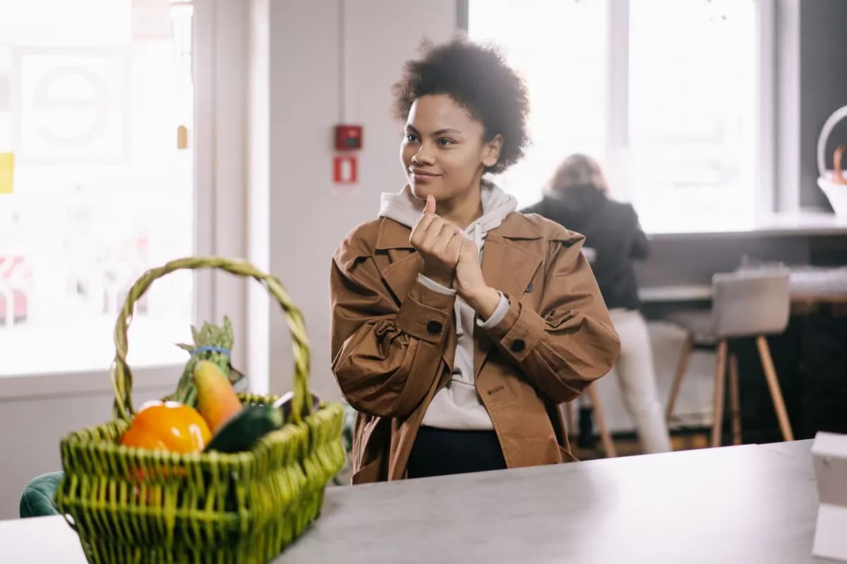 Une jeune femme pensive, près d'un panier de fruits, dans une cuisine lumineuse