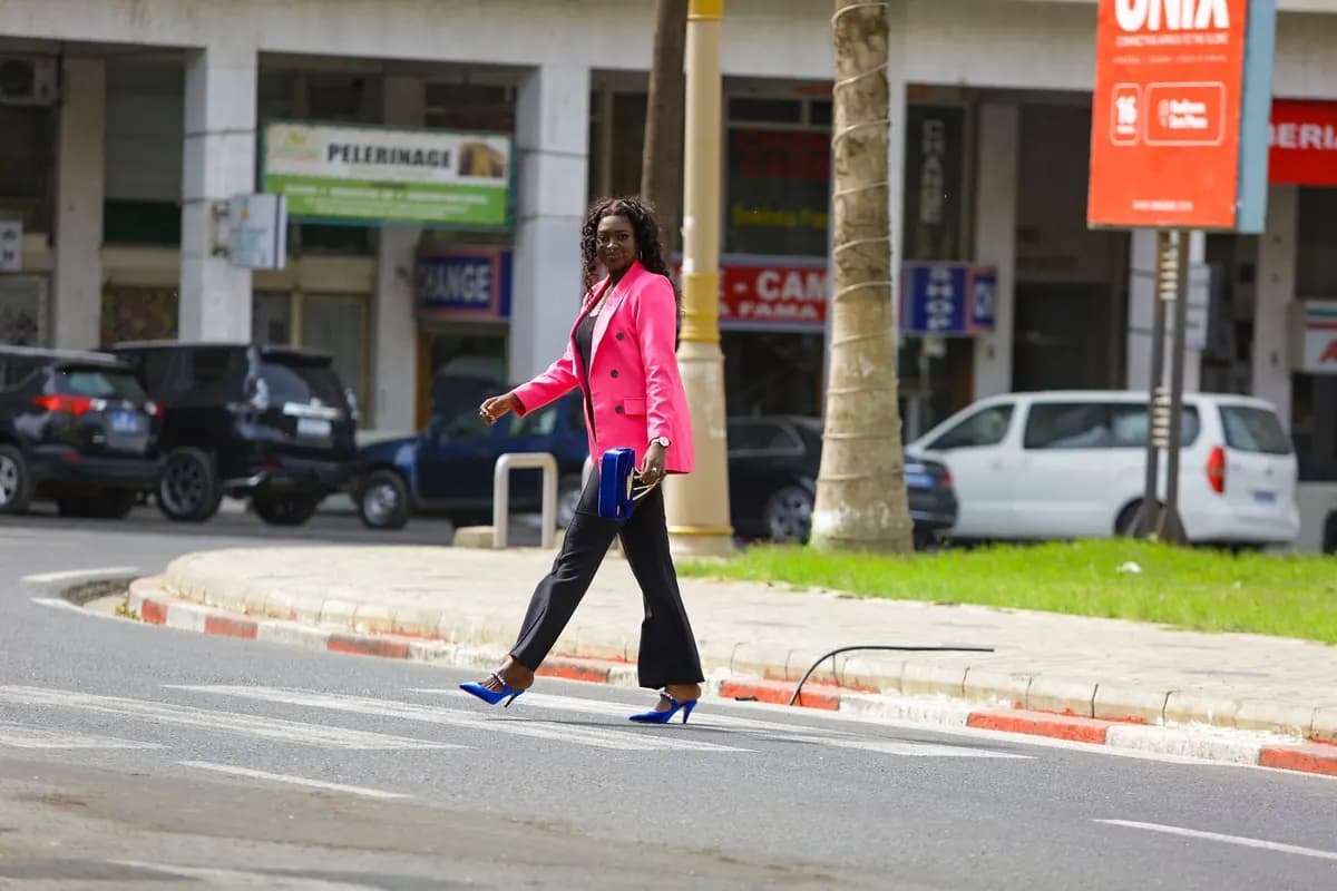 Une femme traverse un passage piéton d'un pas assuré, dans une rue en ville