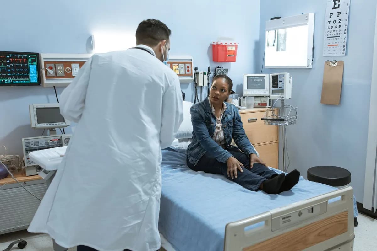 Un médecin reçoit une patiente assise sur la table d'examen d'une salle de consultation
