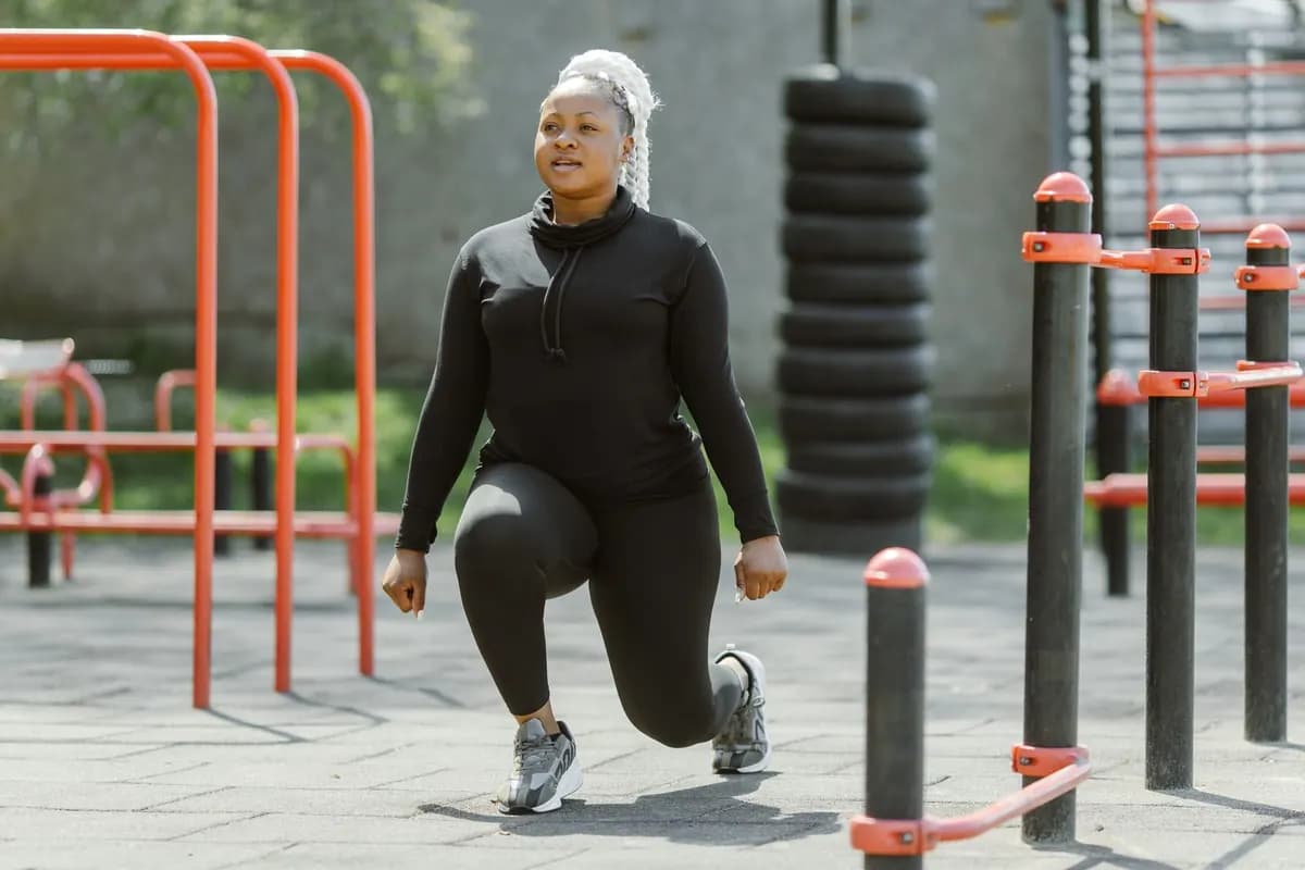Une femme fait des fentes dans un parc d'exercice en plein air