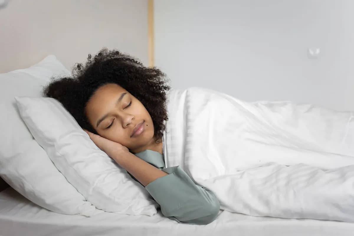 Une jeune femme dort paisiblement dans un lit aux draps blancs