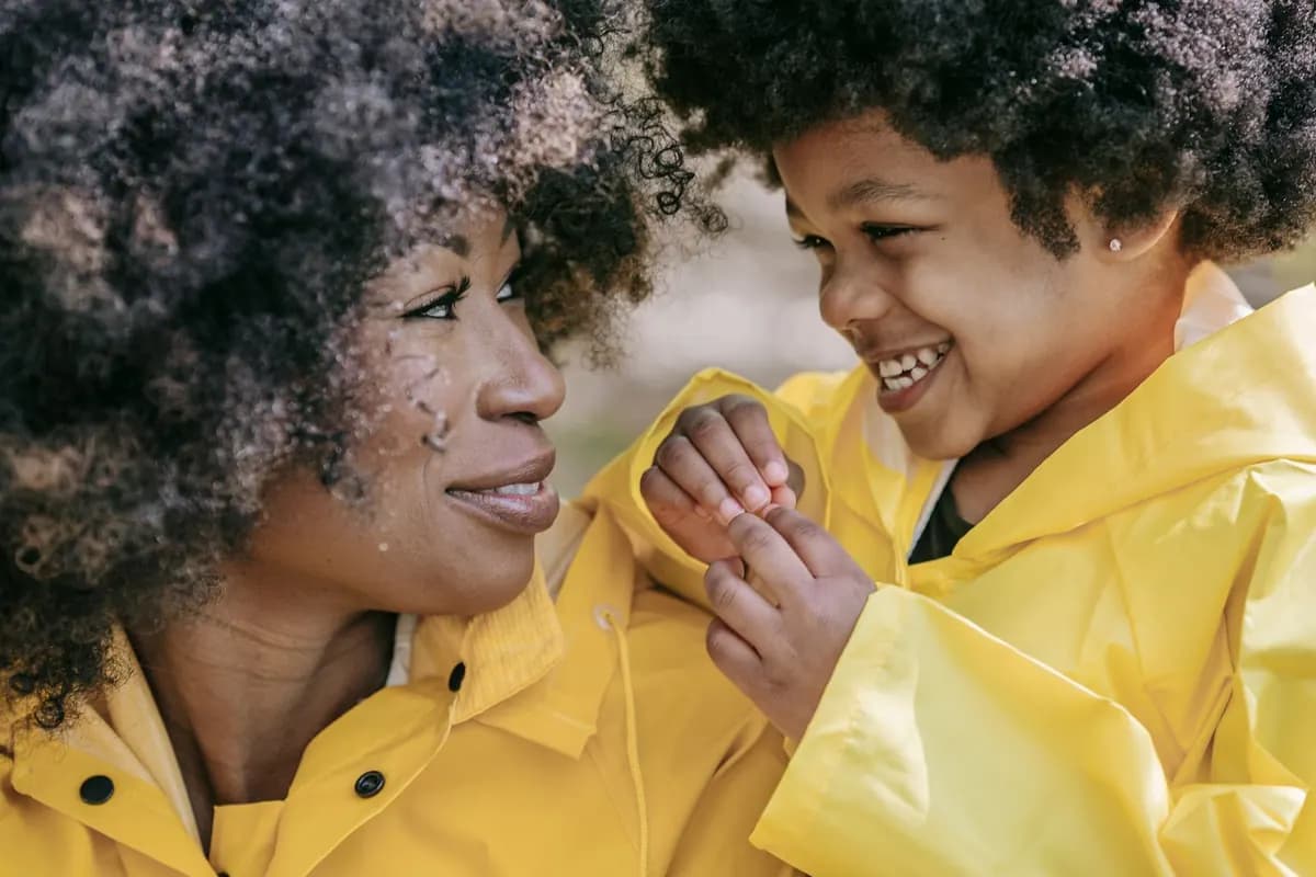 Une mère et son enfant échangent un regard complice et souriant, en plein air