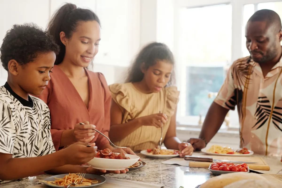 Une famille partage un repas à la maison, parents et enfants autour de la table